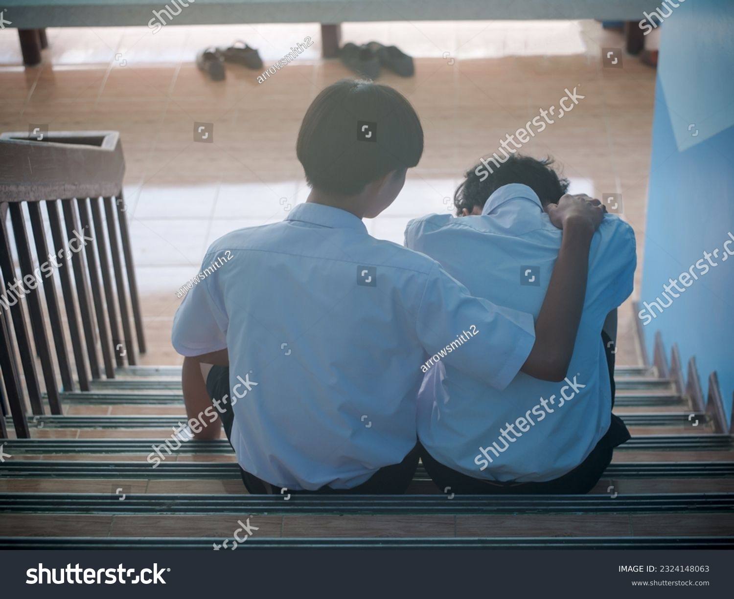 Two students sit down and hug to support a depressed man - a man supports his friend in despair for his love problems. The concept of best friends #2324148063