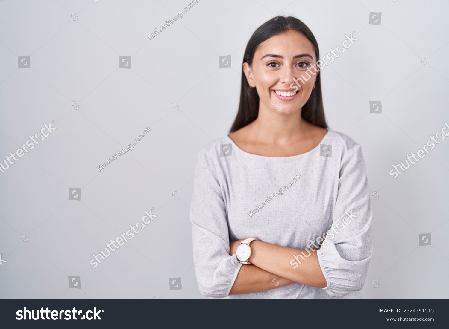 Young hispanic woman standing over white background happy face smiling with crossed arms looking at the camera. positive person.  #2324391515