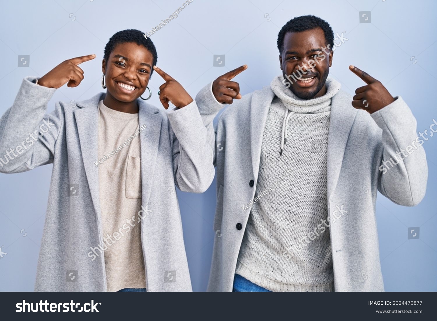 Young african american couple standing over blue background together smiling pointing to head with both hands finger, great idea or thought, good memory  #2324470877