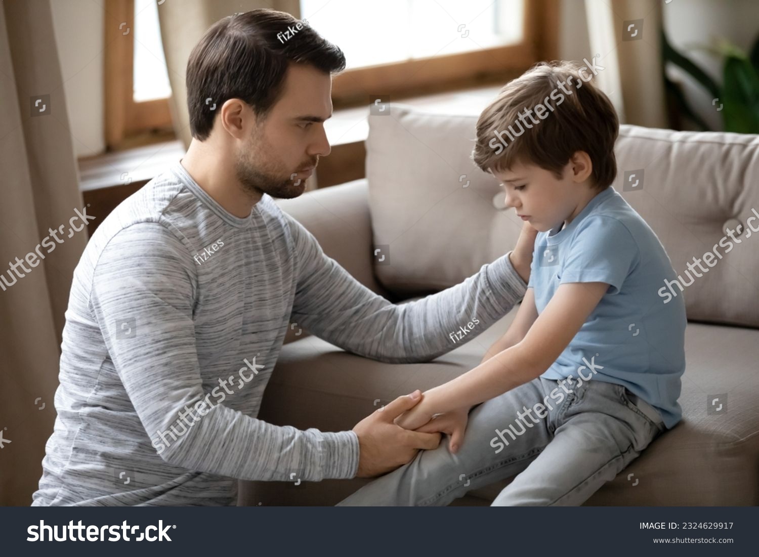 Loving young Caucasian father hug and cuddle unhappy small son, make peace reconcile after family fight. Caring dad comfort support upset sad little boy child feeling bad. Loner, depression concept. #2324629917