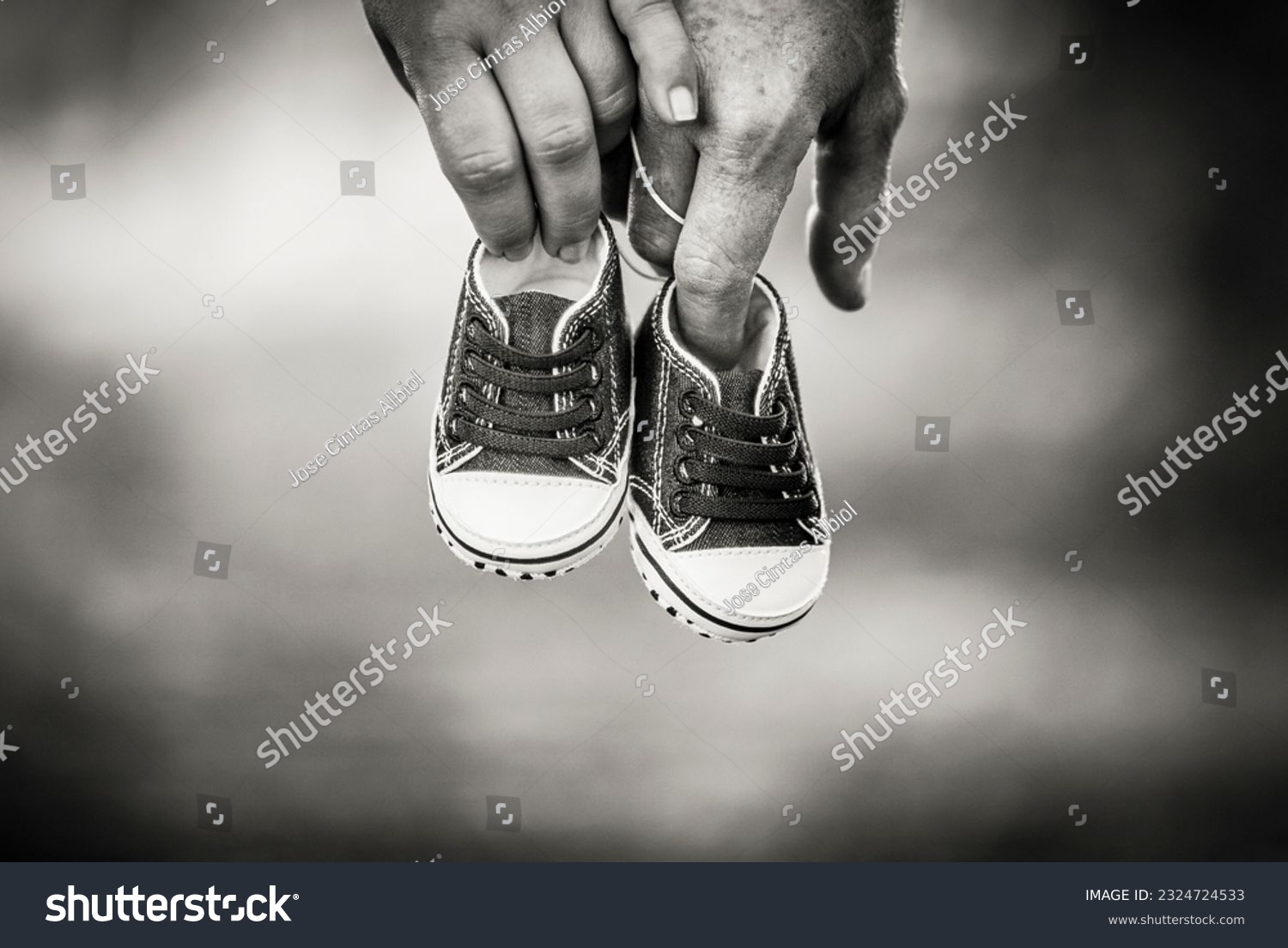 Pregnant couple holding baby shoes with their hands #2324724533
