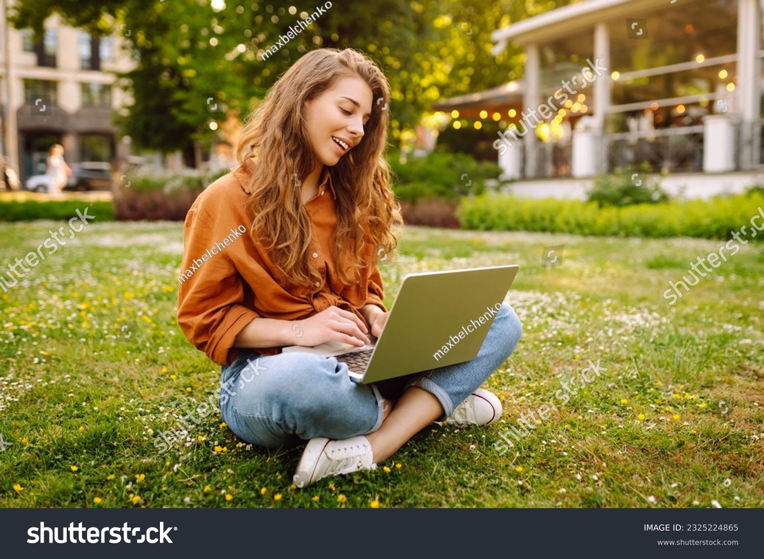 Smiling young woman with a laptop working or studying online outdoor. Concept for education, business, blog or freelance. #2325224865