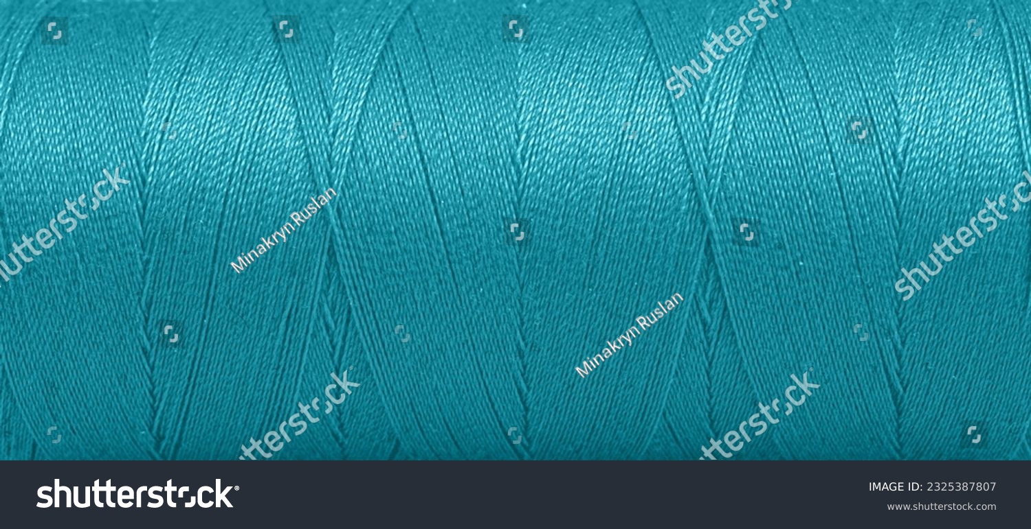 Texture of threads in a spool of turquoise color on a white background close-up #2325387807