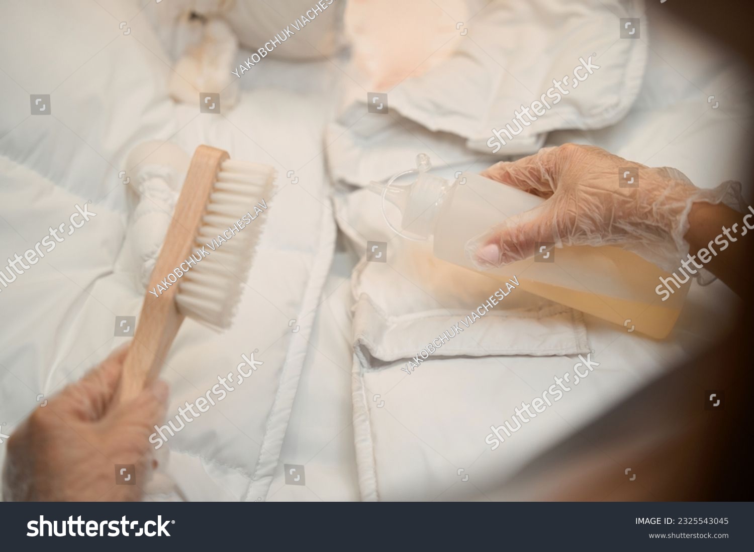 Close-up female hands in protective gloves applying solvent on dirt at jacket #2325543045