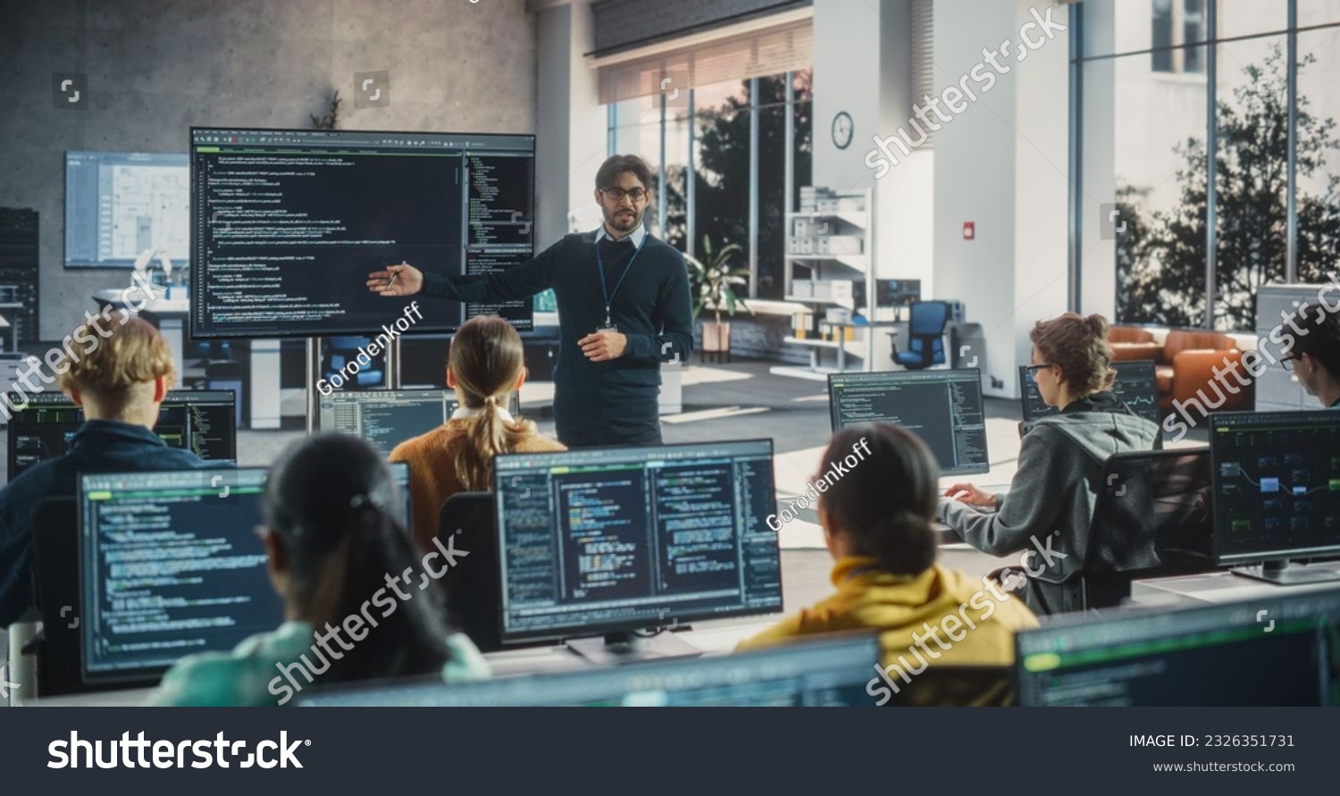 Knowledgeable Teacher Giving a Lecture About Software Engineering to a Group of Smart Diverse University Students. International Undergraduates Sitting Behind Desks with Computers #2326351731