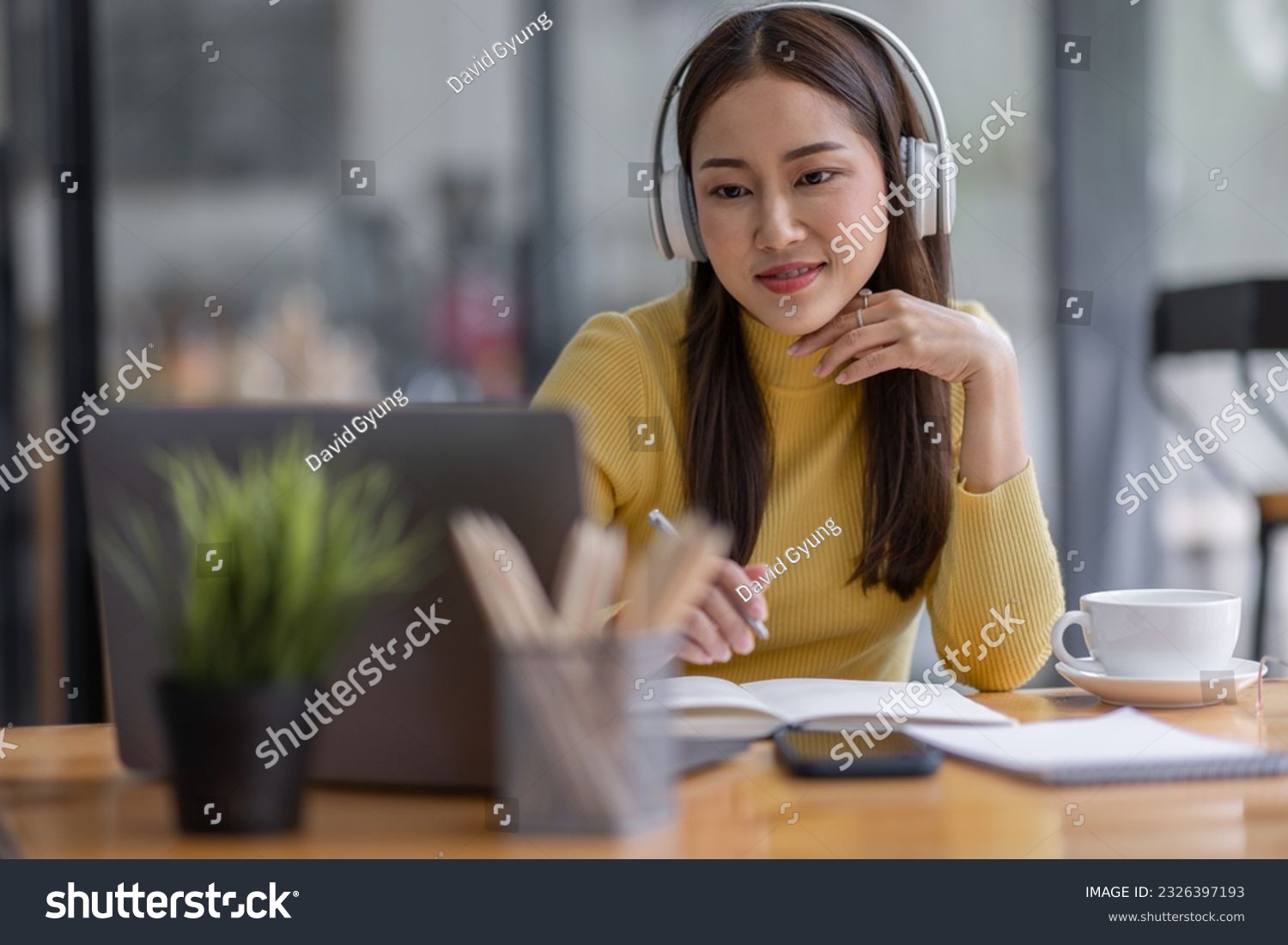 Young adult happy smiling Asian student or business woman wearing headphones talking on online chat meeting using laptop in office or campus, asian female student wear glasses learning remotely. #2326397193
