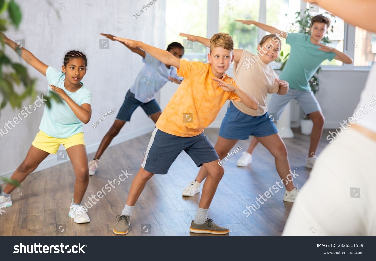 Emotional cheerful tween boy enjoying contemporary dance with group of children, showcasing dabbing move.. #2326511559