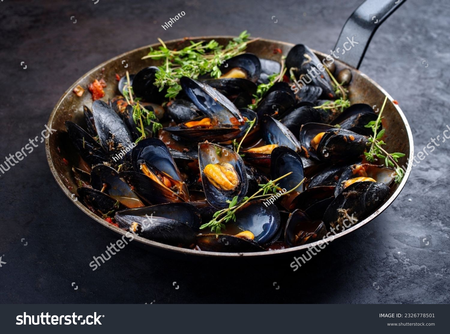 Traditional barbecue Italian blue mussel in tomato red wine sauce with herb and garlic as close-up in a rustic iron pan  #2326778501