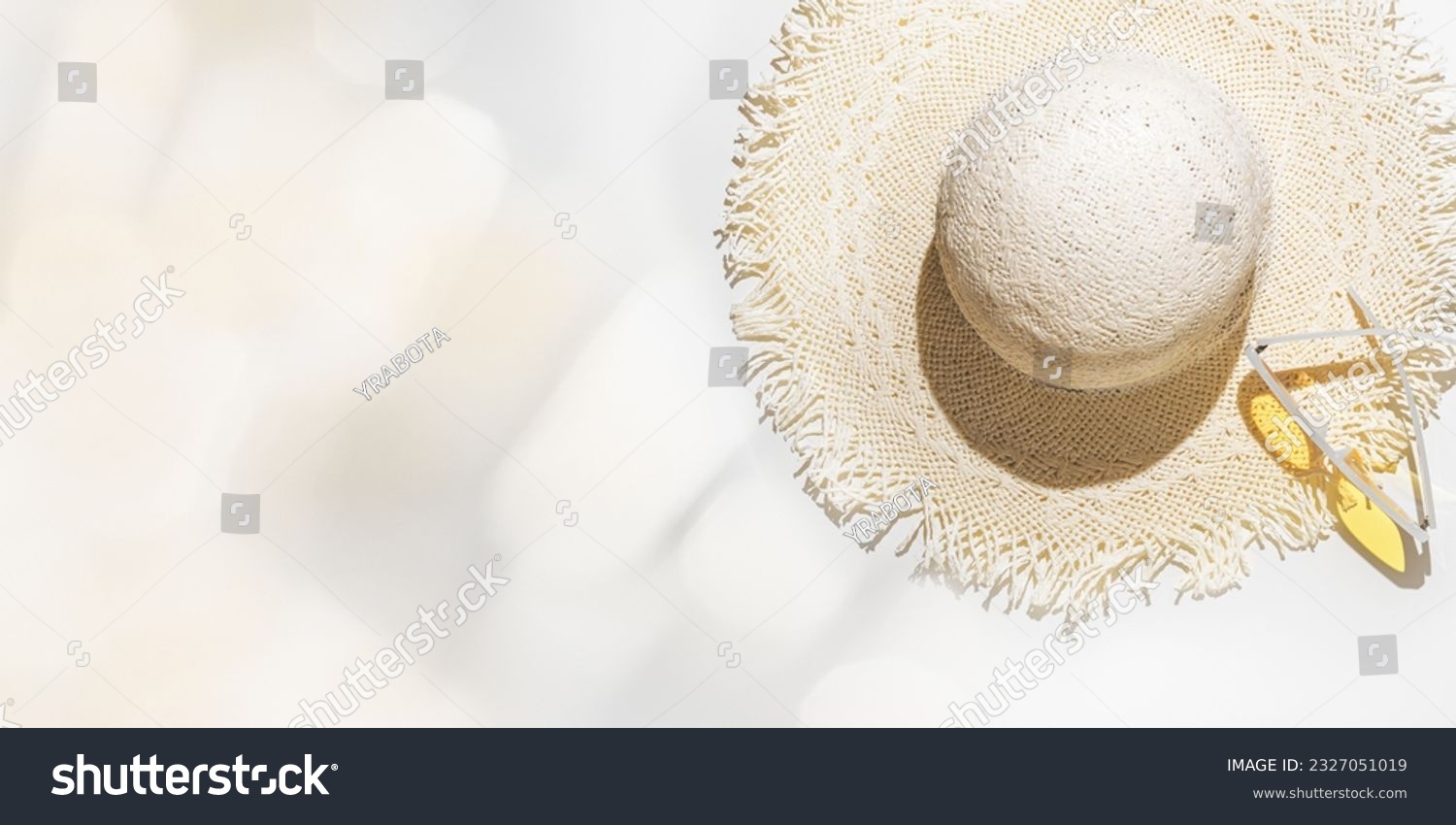 Summer flat lay straw sun hat and yellow sunglasses at sunlight on  light grey background with blurred bokeh glare as copy space. Aesthetic Life style summer holidays photo, beige pastel color banner #2327051019