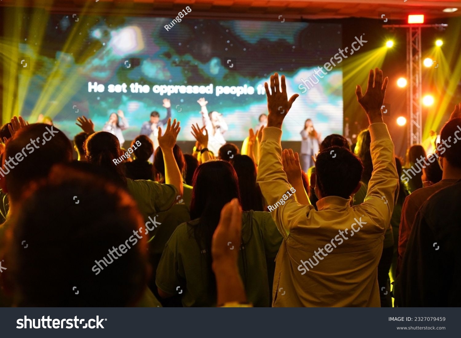 Worship includes music and numerous people lifting their hands in praise to God on stage  #2327079459