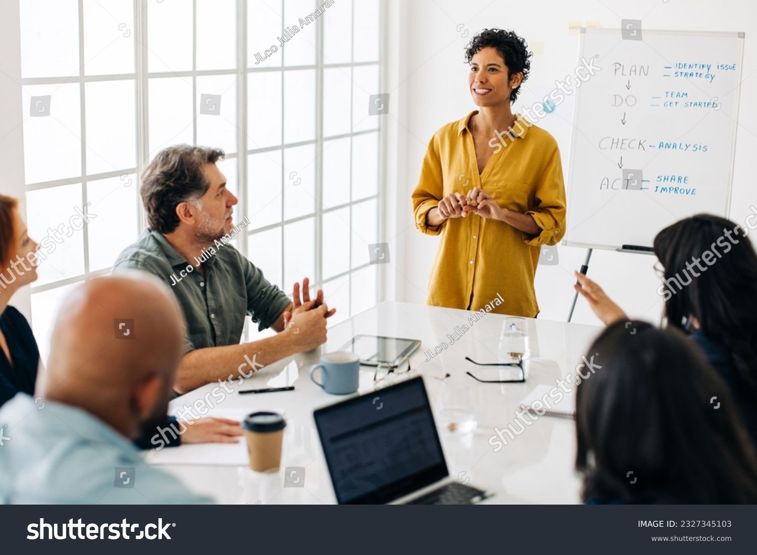 Woman having a discussion with her business team in a boardroom. Black business woman leading a meeting in an office. Female project manager giving a speech to a group of professionals. #2327345103