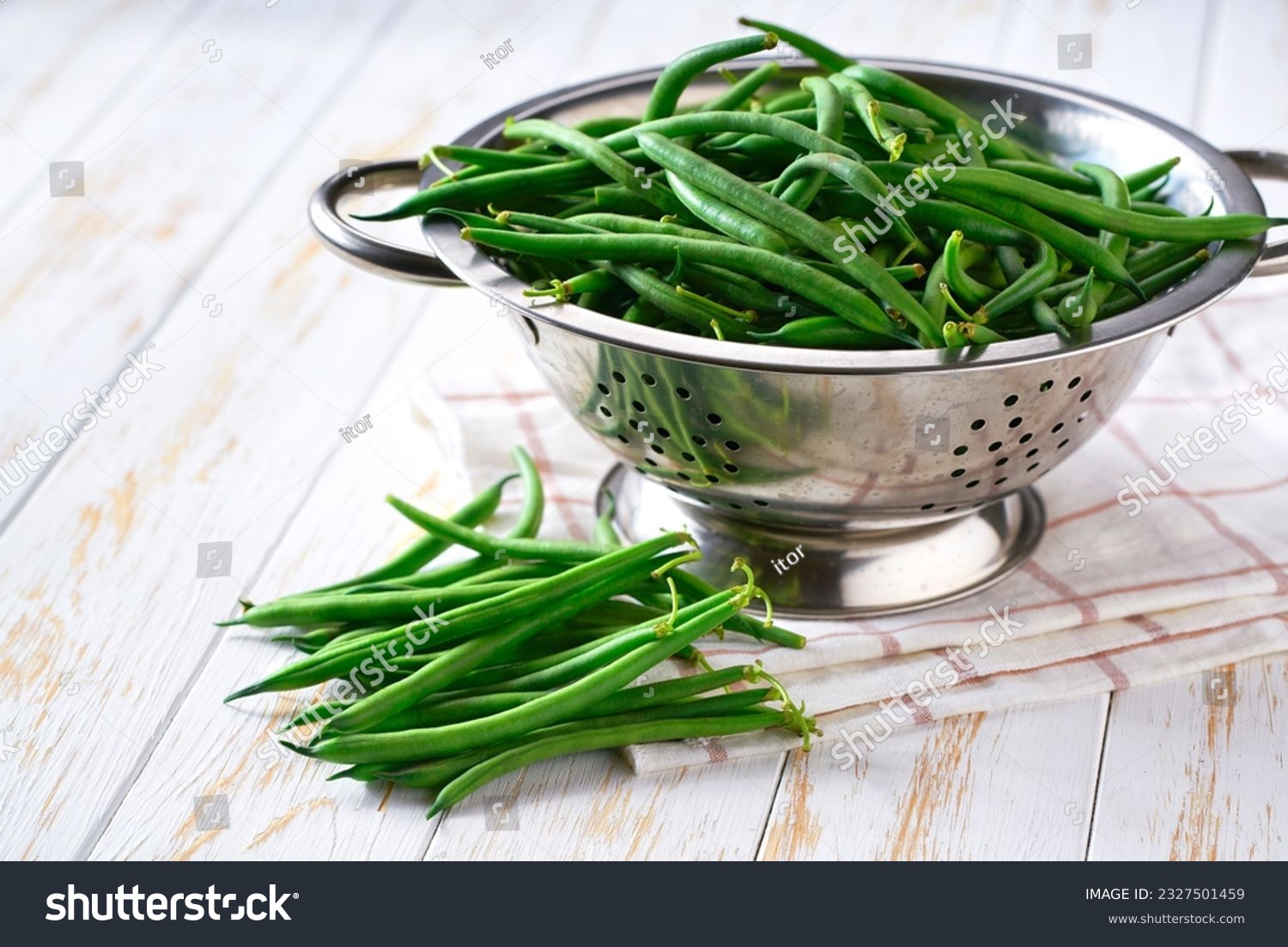 green beans in a steel strainer sieve metal on a white wooden table, selective focus. #2327501459