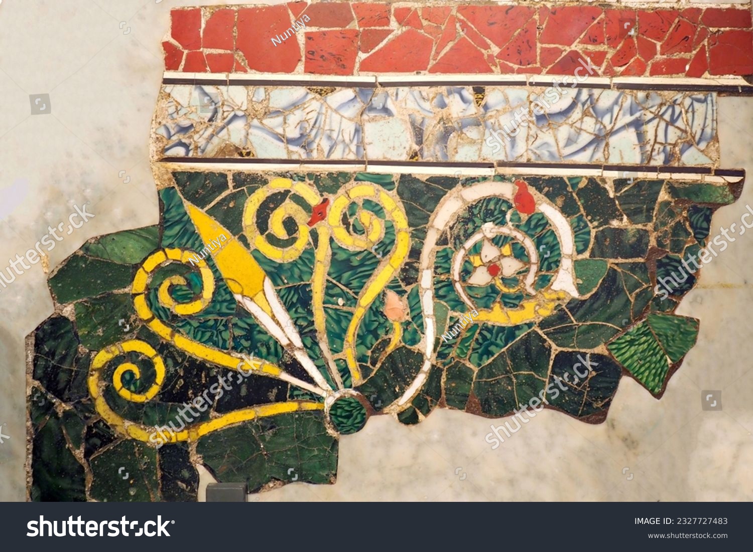 Ancient wall adorned with a vibrant handmade freeform-tiles mosaic, showcasing a floral pattern. #2327727483