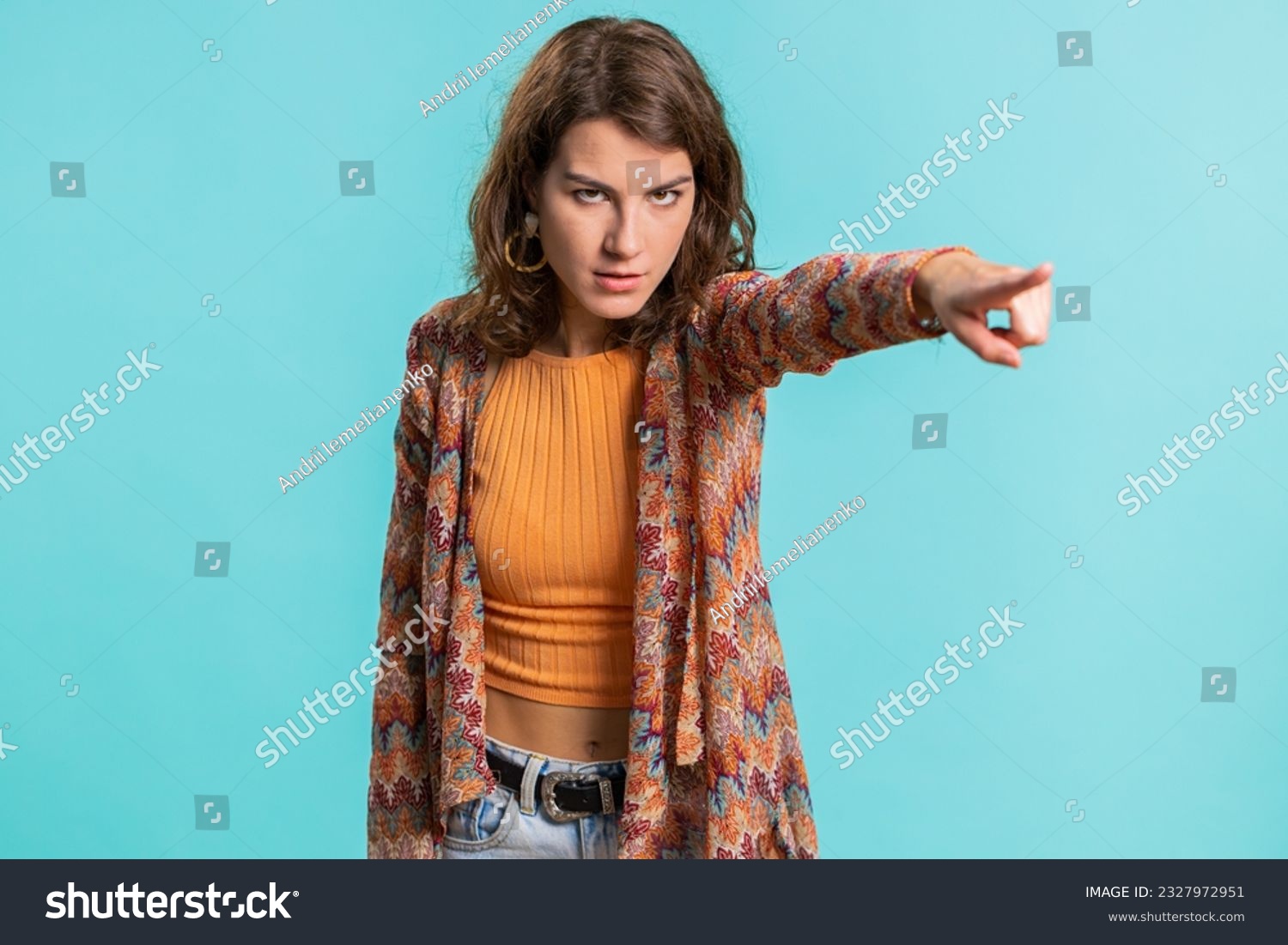 Get out of here. You are fired. Young Caucasian woman pointing finger away asking to leave her alone, strict boss firing, conflict, quarrel. Brunette girl isolated on blue studio background indoors #2327972951