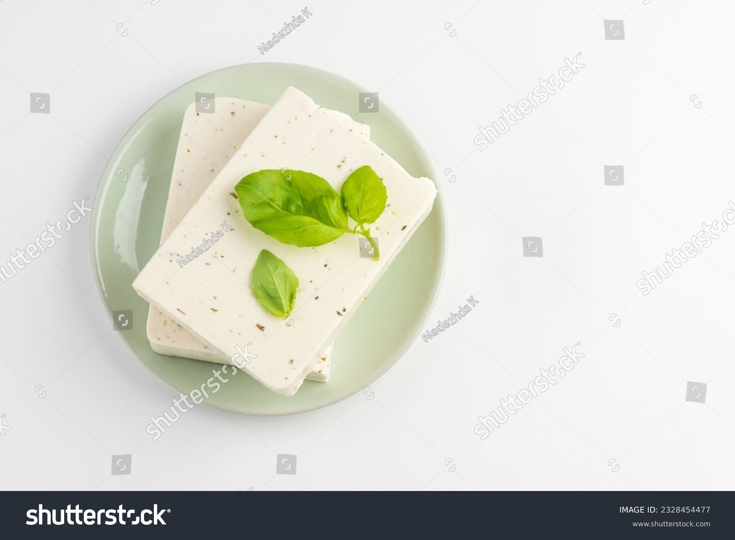 Top view of  tofu, paneer or soy cheese with fresh basil leaves in a green plate isolated with copy space #2328454477