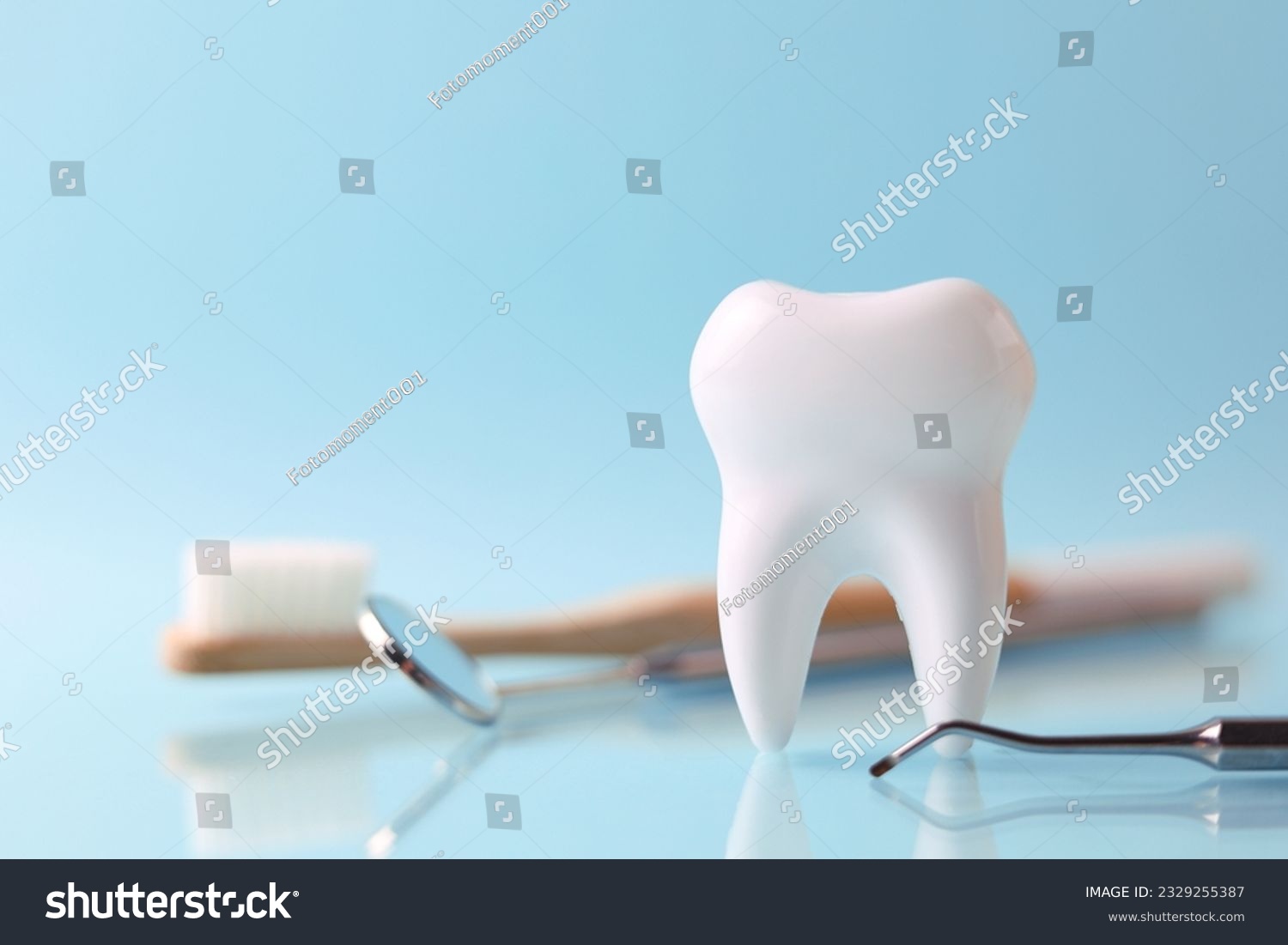 Dentistry concept. Model of a tooth and dental instruments on a colored background with space for text.  #2329255387