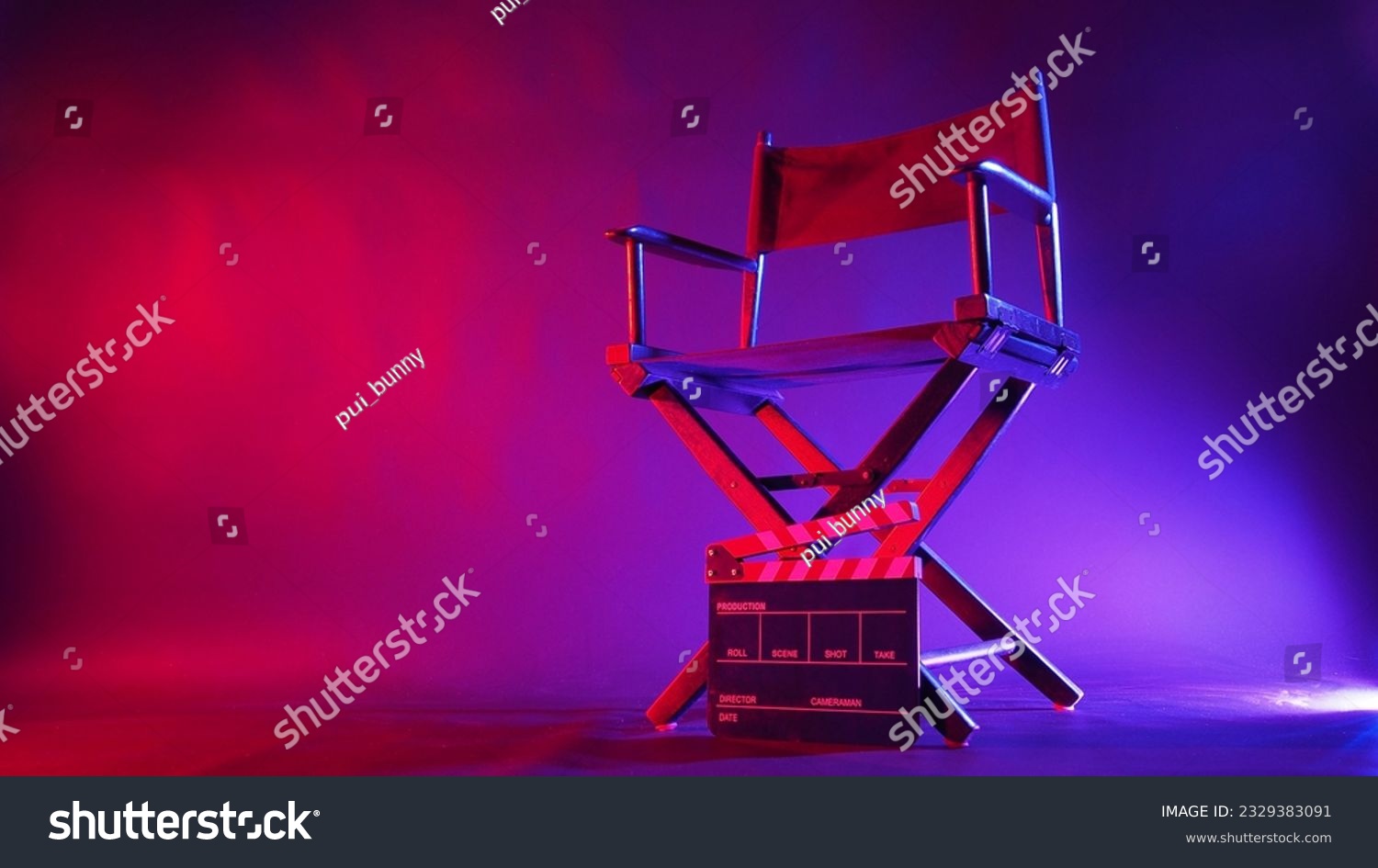 Director chair and clapper board in red and blue light color with black background #2329383091