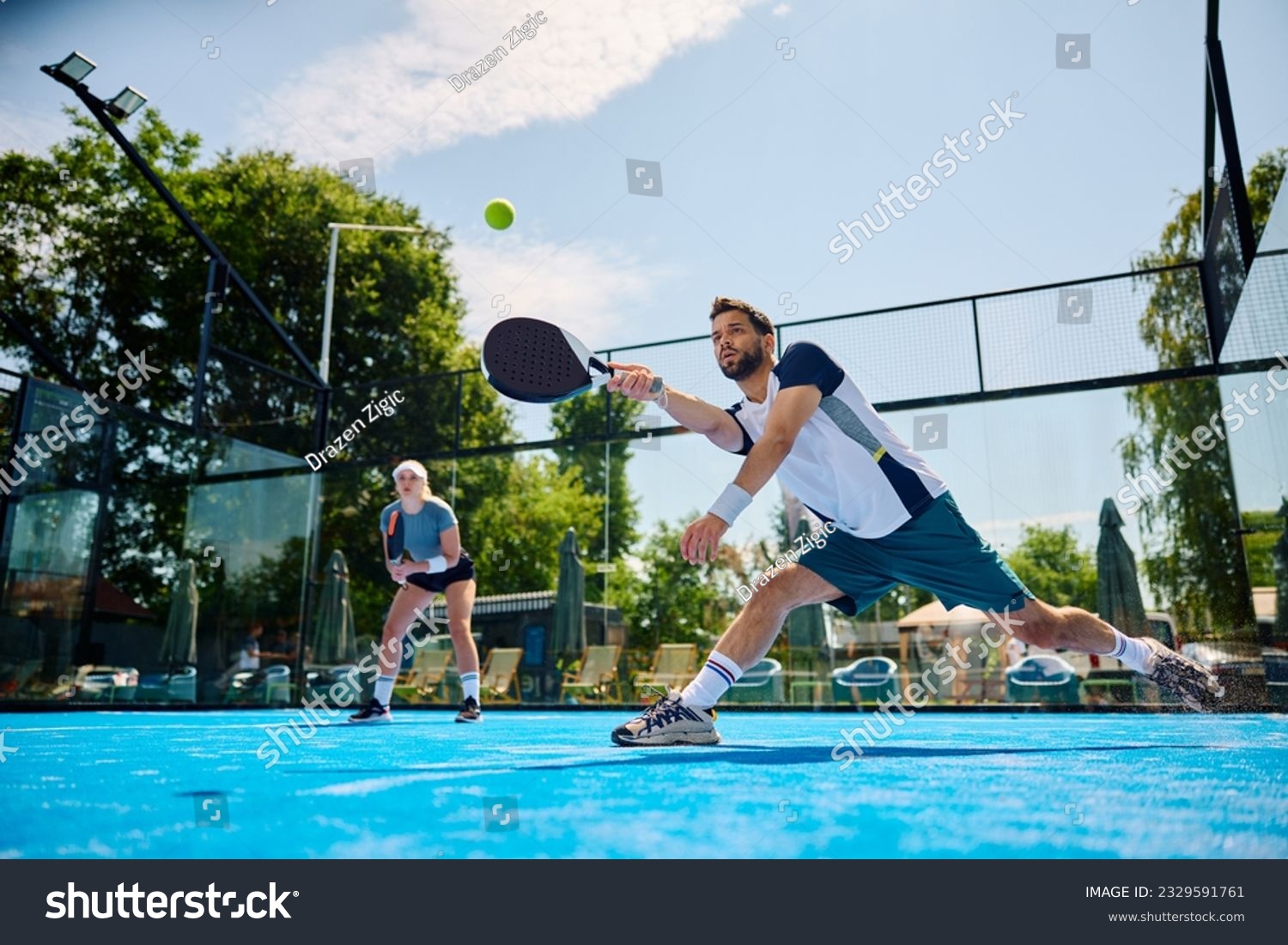 Young athlete playing padel in mixed doubles on outdoor court. Copy space. #2329591761