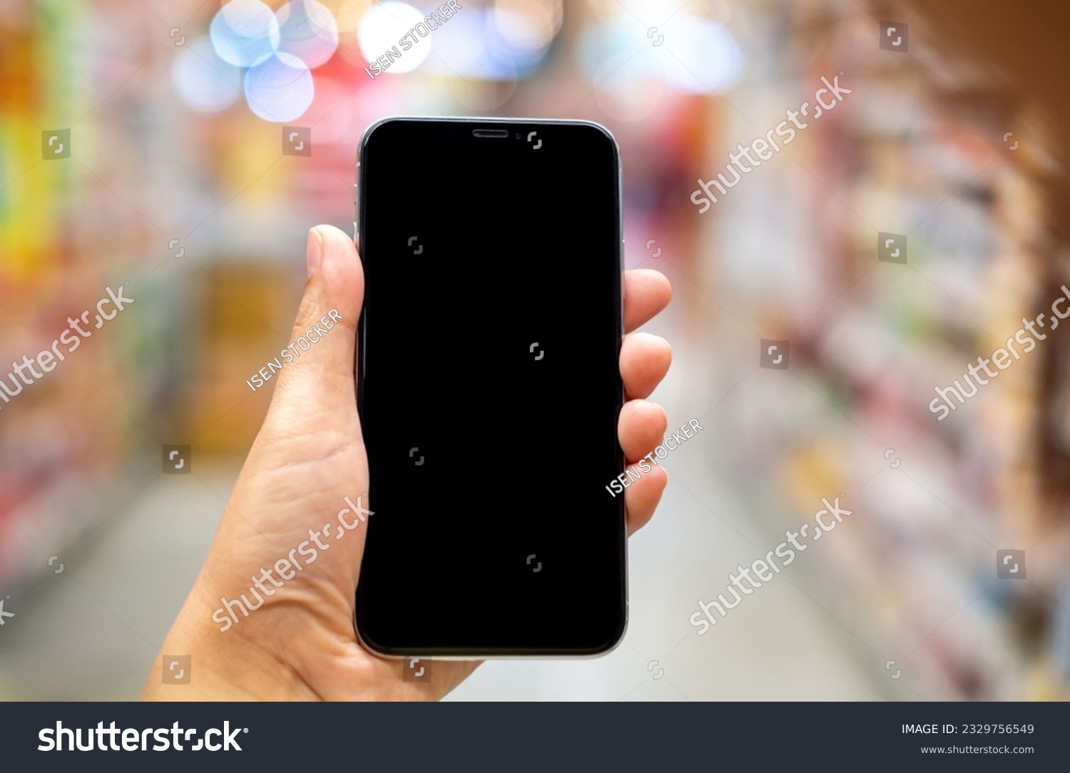 Hand holding black mockup smartphone and blurred background whit bokeh, telephone on the hand for presentation product and activities, life slyle concept #2329756549