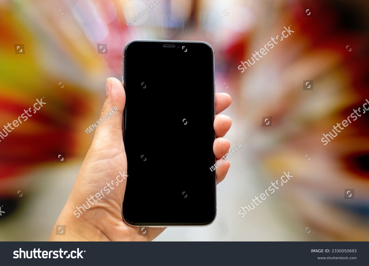 Hand holding black mockup smartphone and blurred background whit bokeh, telephone on the hand for presentation product and activities, life slyle concept #2330050693