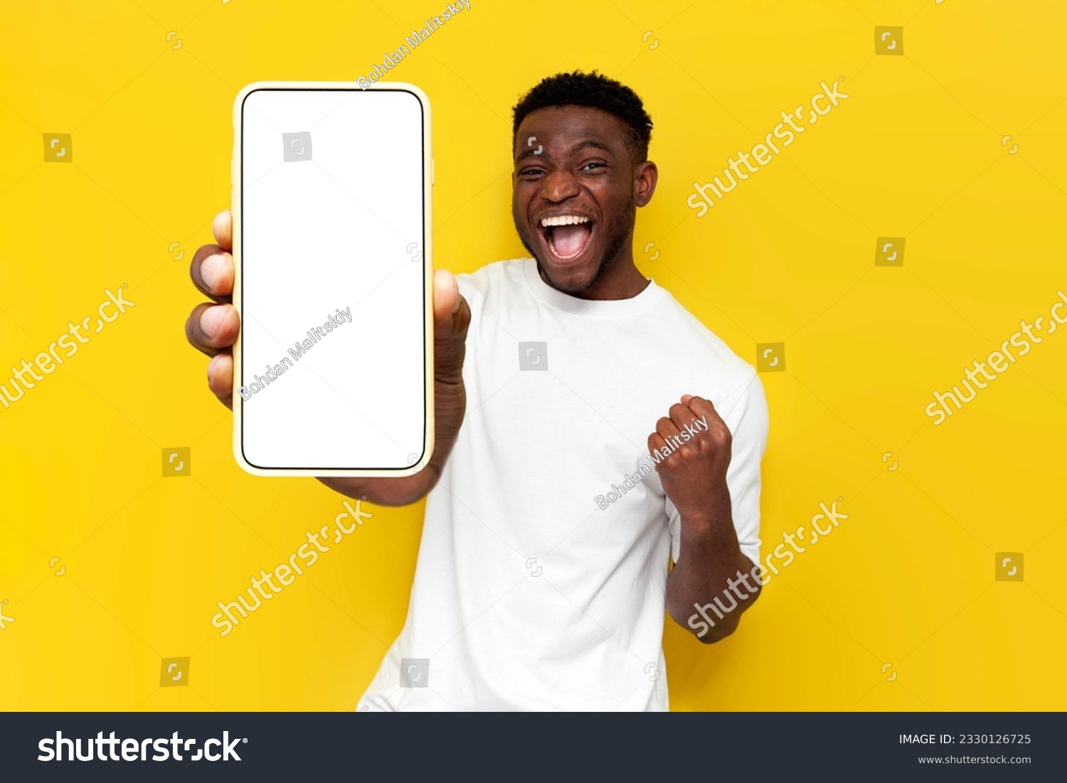 african american man celebrating victory and showing blank screen of smartphone on yellow isolated background, winner guy rejoices in success and luck and advertises copy space on phone display #2330126725