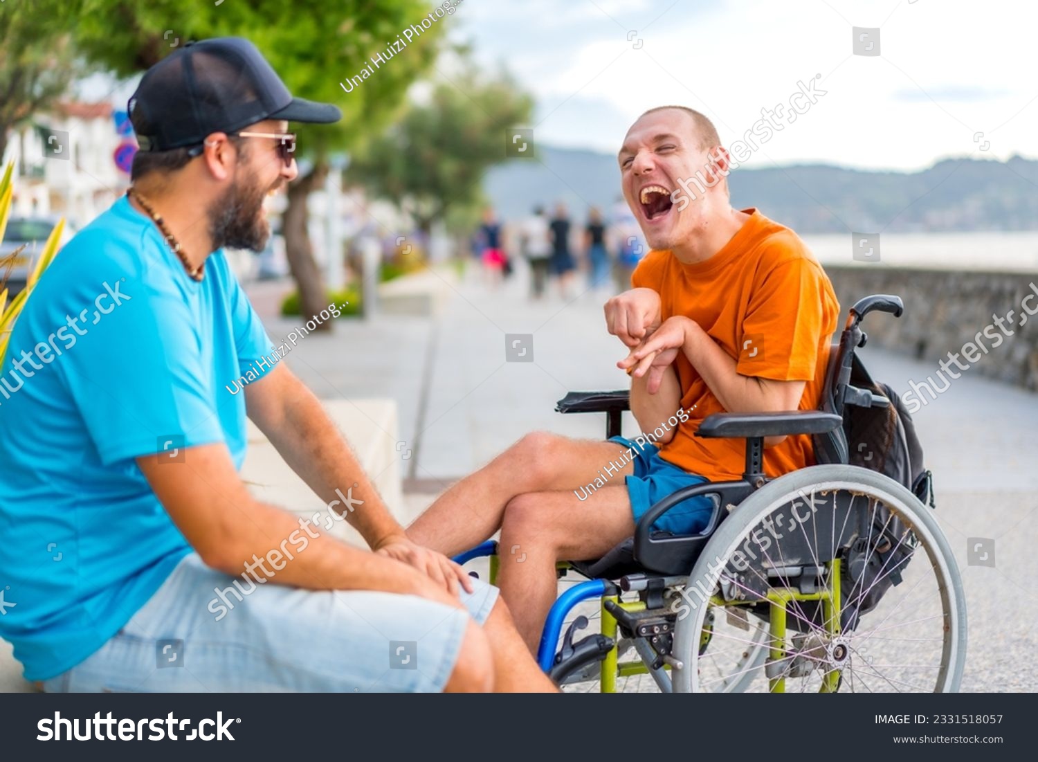 A disabled person in a wheelchair with a friend on summer vacation having fun laughing a lot #2331518057