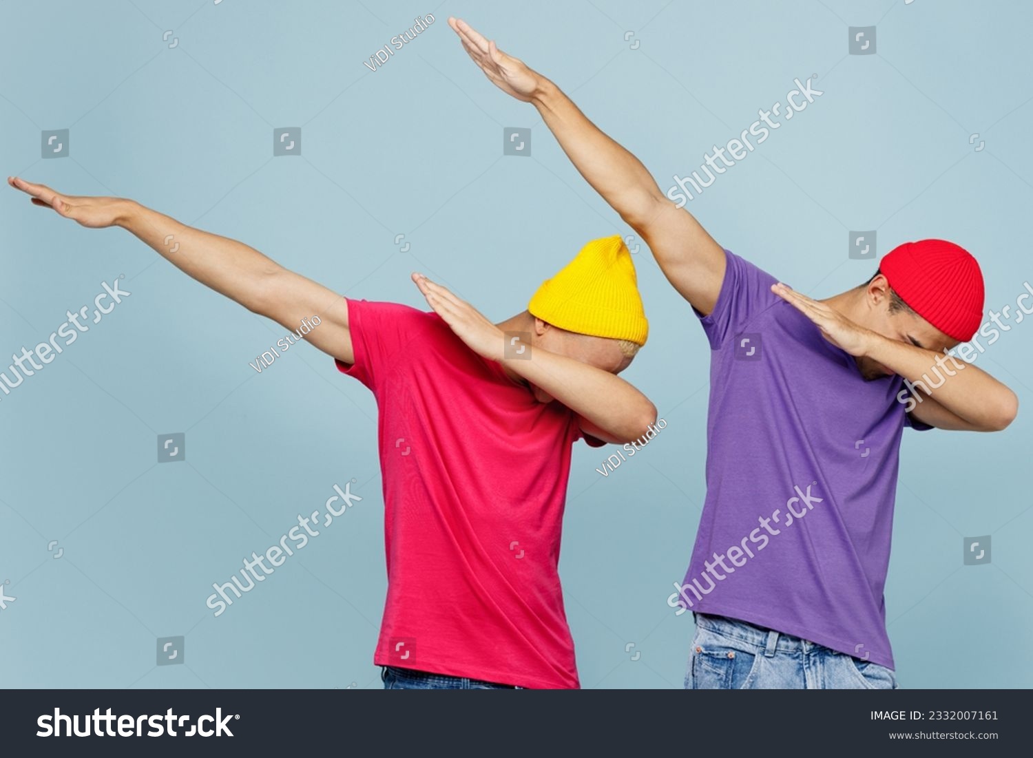 Young cool couple two friends men wear casual clothes together doing dab hip hop dance hands move gesture youth sign hide cover face isolated on pastel plain light blue cyan background studio portrait #2332007161