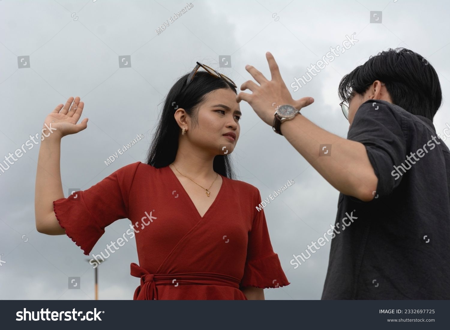 An annoyed woman threatens to slap her submissive and meek boyfriend during an argument. Outdoor scene. #2332697725