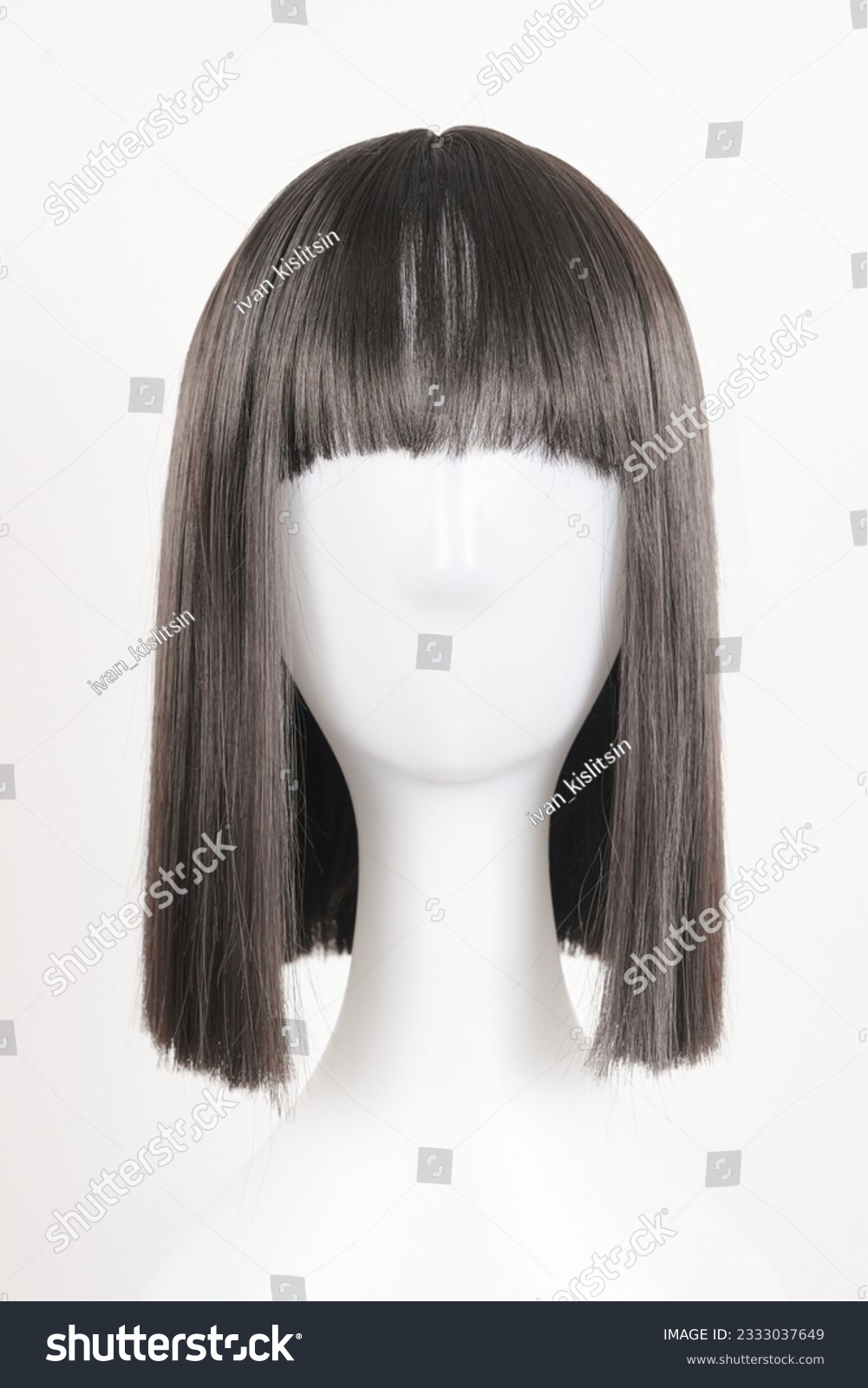Natural looking black wig on white mannequin head. Medium length straight hair with bangs on the metal wig holder isolated on white background, front view #2333037649