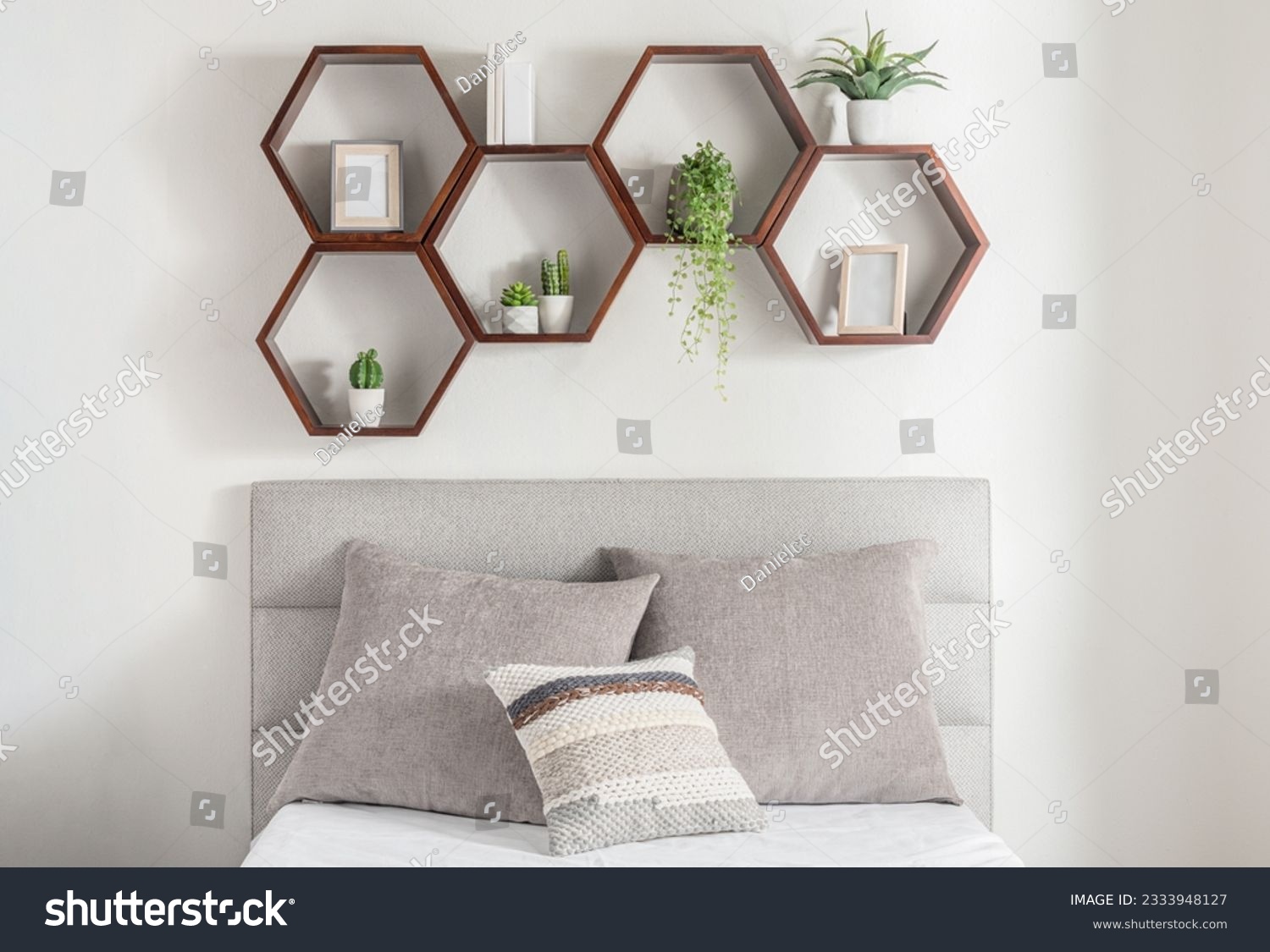 An inviting bedroom features suspended hexagonal wooden shelves above the bed, accented by plants for a tranquil feel #2333948127