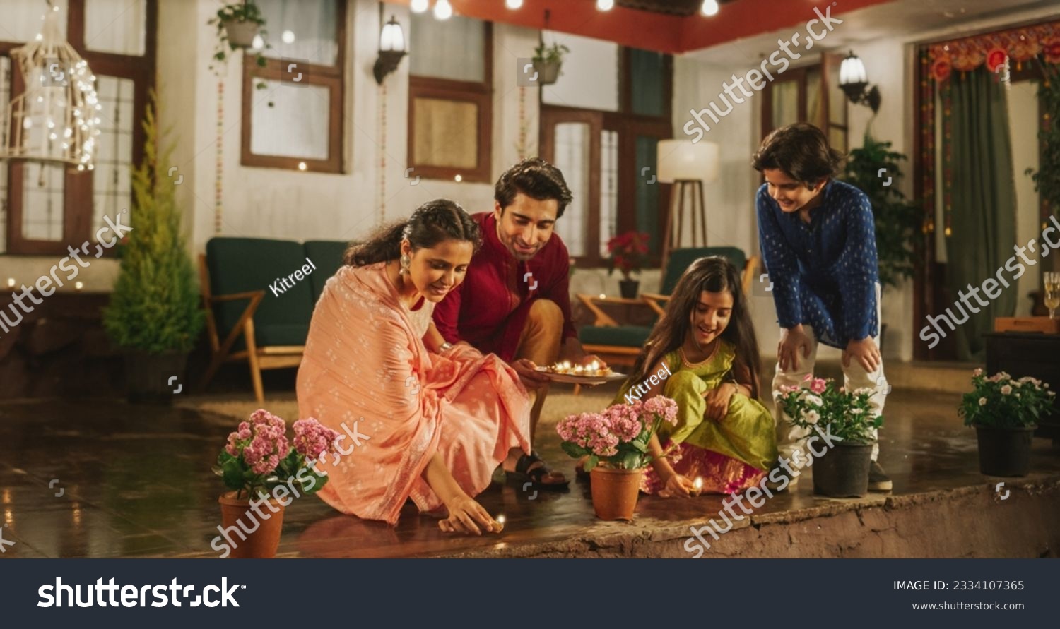 Portrait of an Indian Family Celebrating Divali by Putting Lamps in Their Backyard. Happy Young Parents and Their Exited Children Participating in Hindu Religious Festivities, Festival of Lights #2334107365
