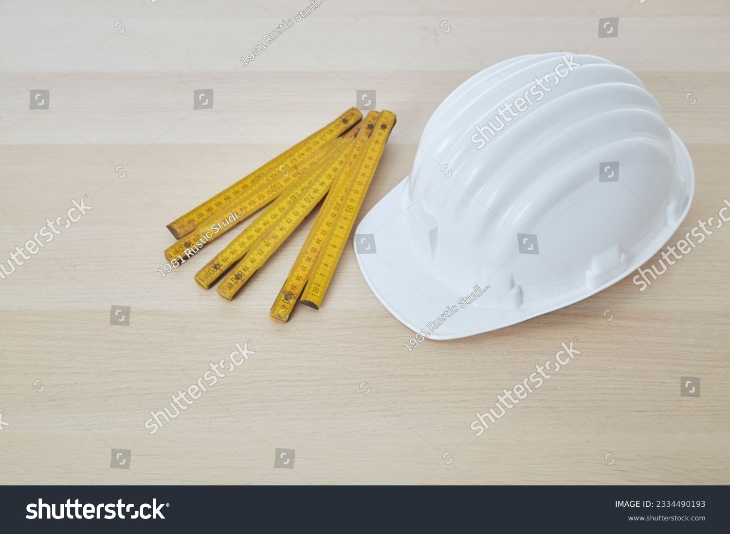 Construction tools and a white hard hat with a measuring stick, paper house building plan on a wooden work table copy space for text #2334490193