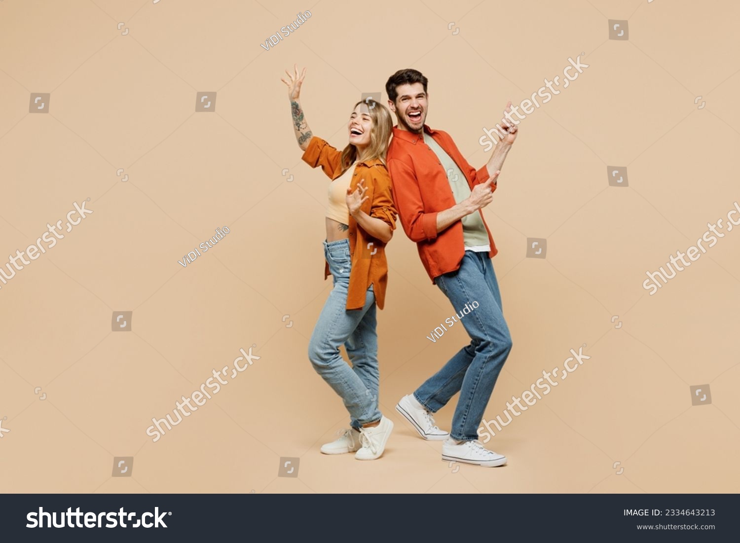 Full body fun young couple two friends family man woman wear casual clothes point index finger aside on area waving hand together isolated on pastel plain light beige color background studio portrait #2334643213