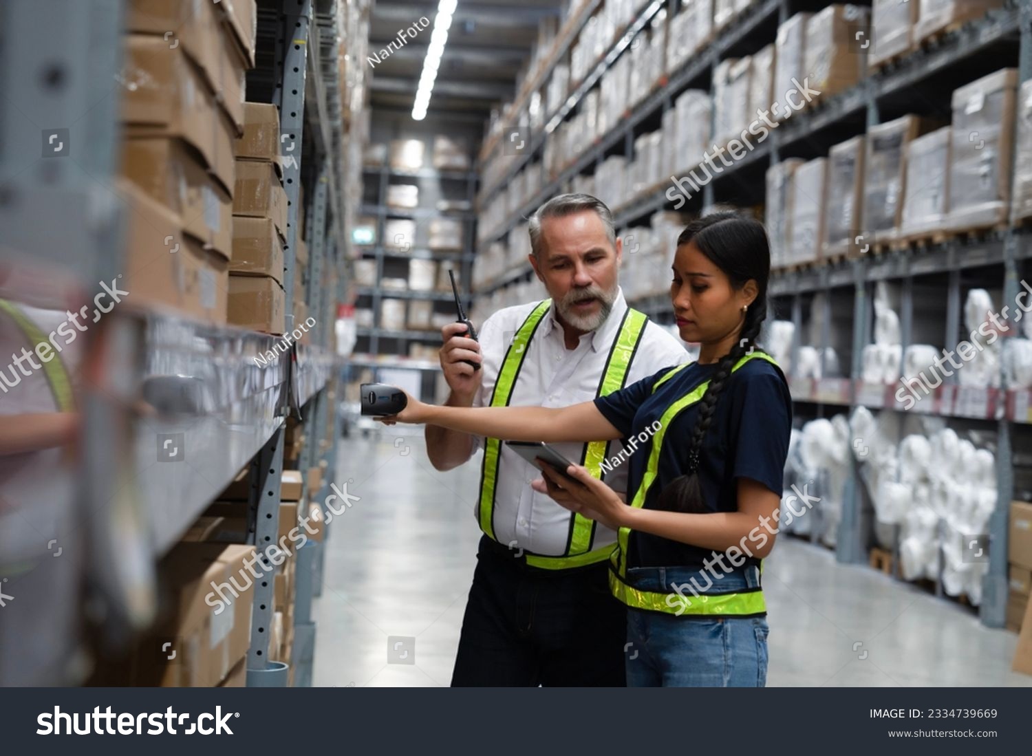 Warehouse manager coaching new employee to find  shipment from online inventory system and using scanner to scan barcode to check real time stock balancing. Online stock application for worker to use #2334739669