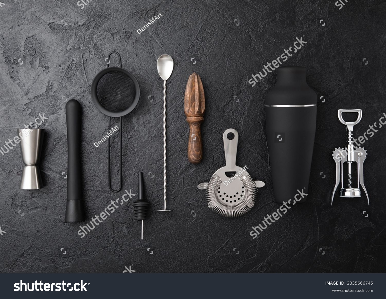 Cocktail utensils black matt steel set on black board background..Shaker,wine opener,spoon,strainer,muddler and jigger with wooden manual juicer. #2335666745