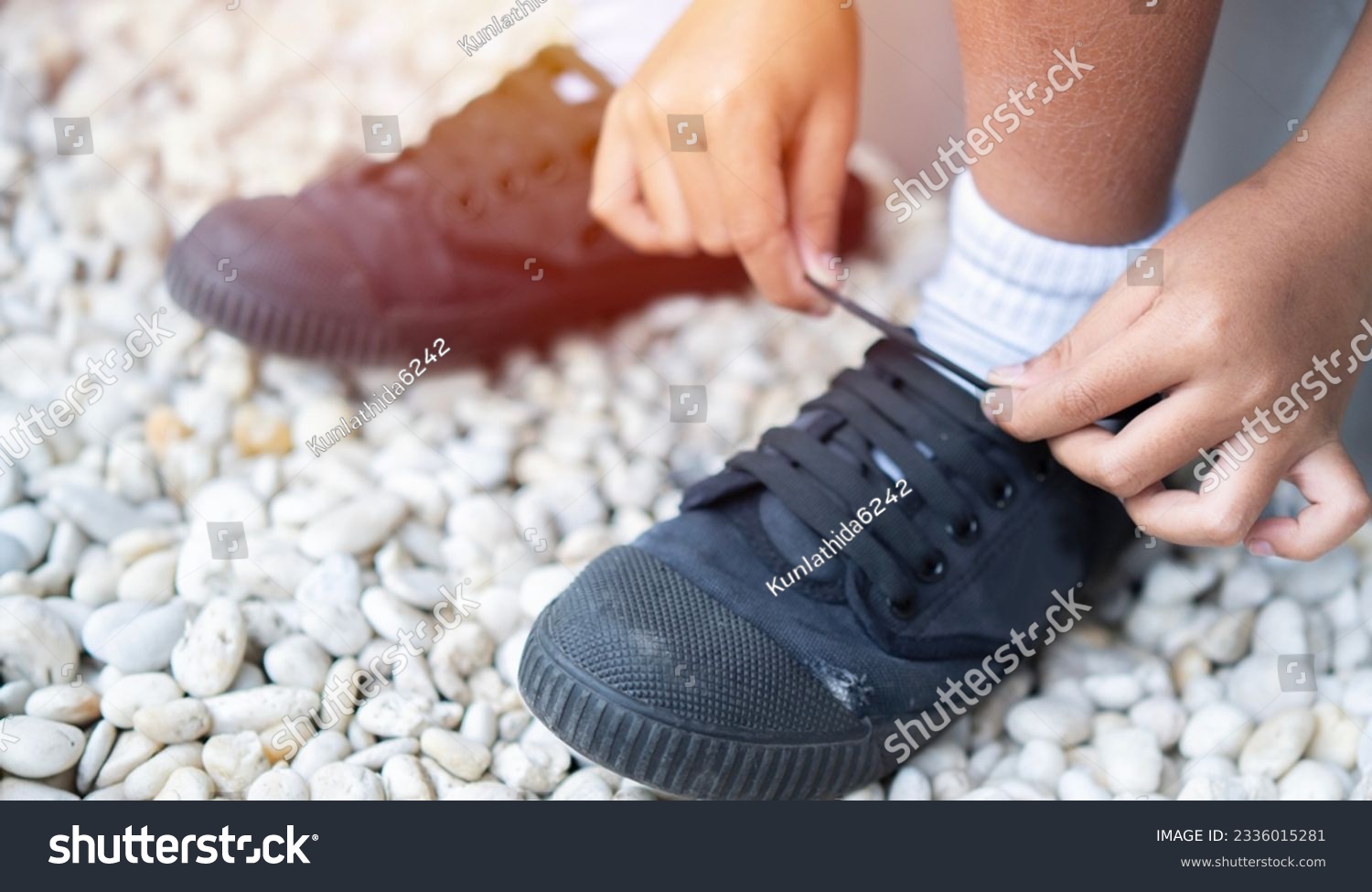 Cropped image of student boy shoes in uniform getting ready for school by tying his shoelaces. Early Education concept. Selective focus. #2336015281