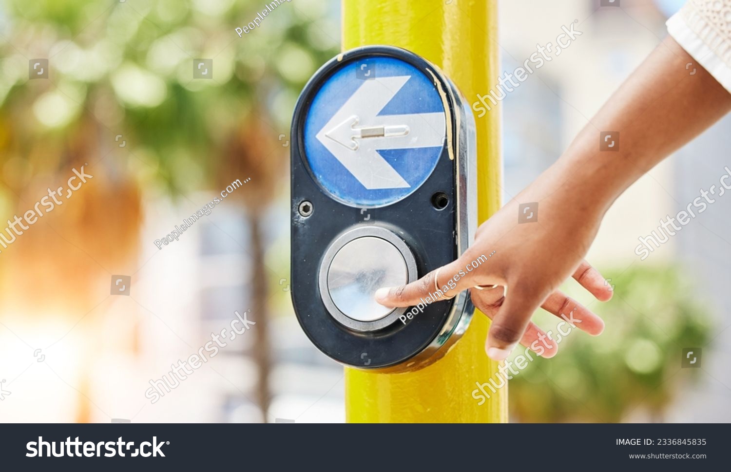 Crosswalk, arrow and button with hand of woman in city for traffic light, intersection and safety. Travel, sign and stop with person at pedestrian crossing in street for press, transport and warning #2336845835