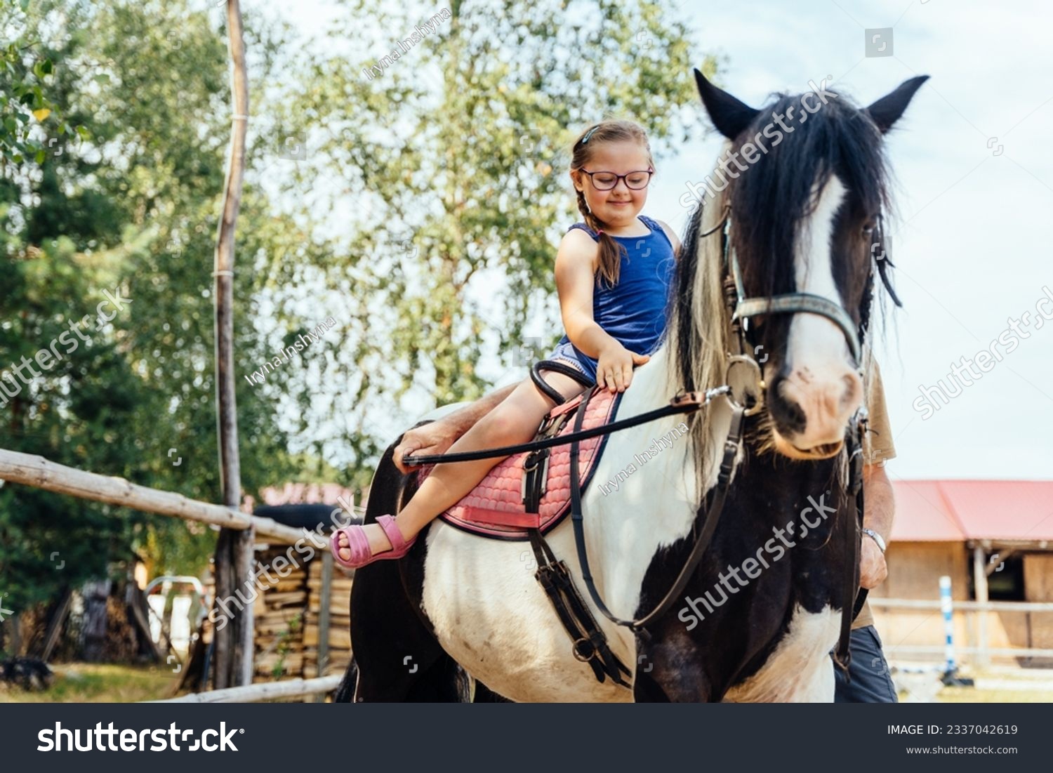 Cute girl on a red horse outdoor. Hippotherapy for young children with down syndrome, therapy after many serious diseases. #2337042619