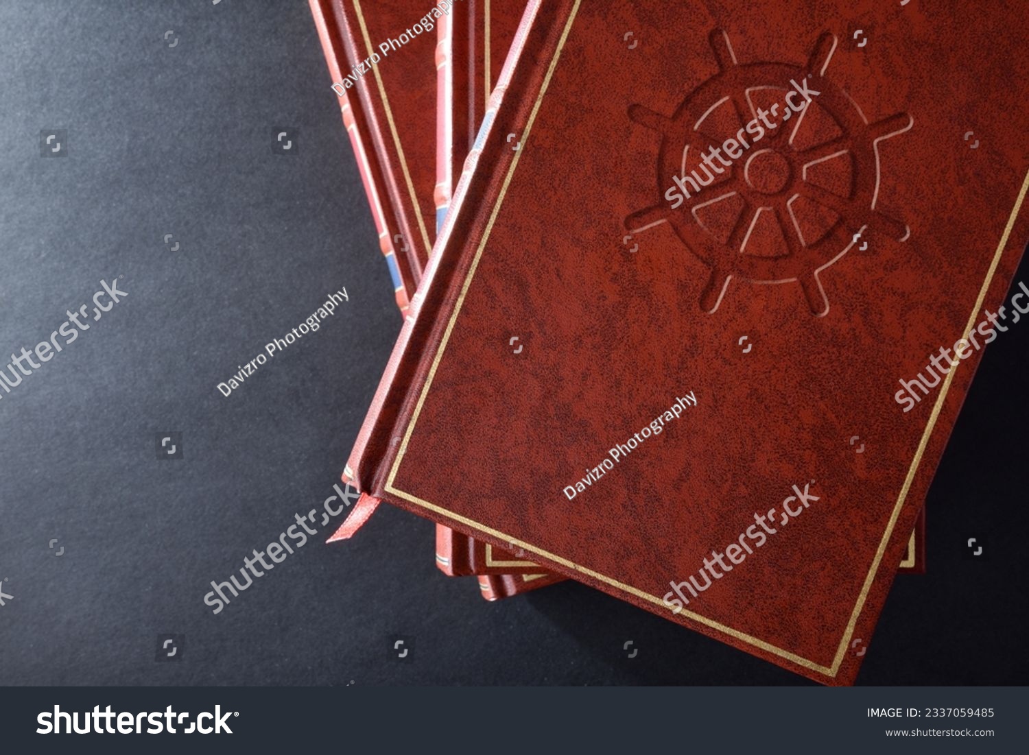 Stack of books with brown leather cover with engraved symbol of buddhist culture and religion on black table. Top view. #2337059485