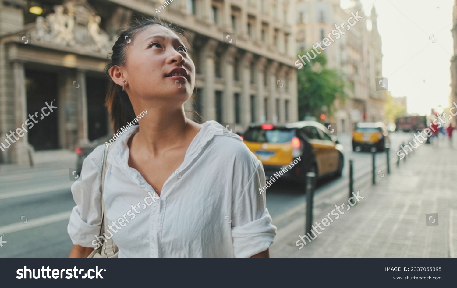 Young woman walks down the street and looks around #2337065395