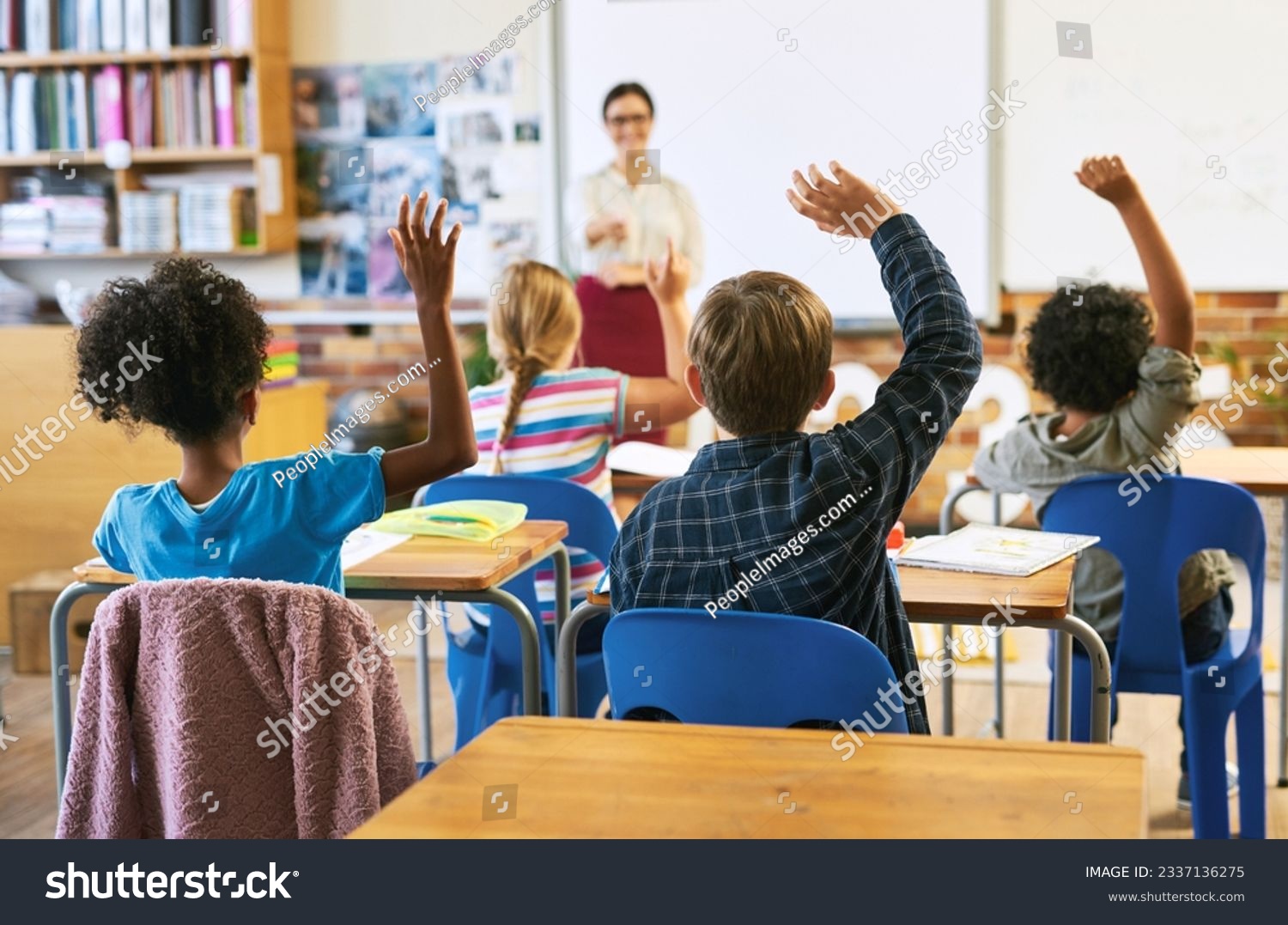 Education, question with group of children in classroom and raise their hands to answer. Learning or support, diversity and teacher teaching with young students in class of school building together #2337136275