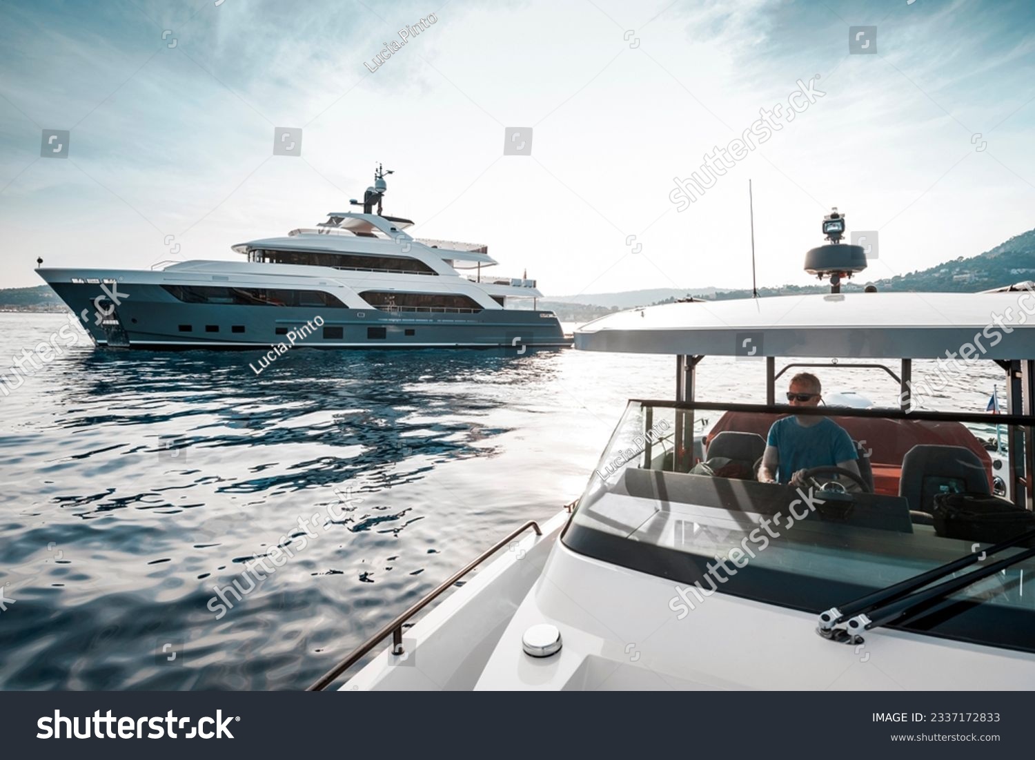 Superyacht deckhand crew on duty, driving chase boat tender next to a 38 meter modern superyacht at anchor in the Bay of Saint-Jean-Cap-Ferrat, south of France #2337172833