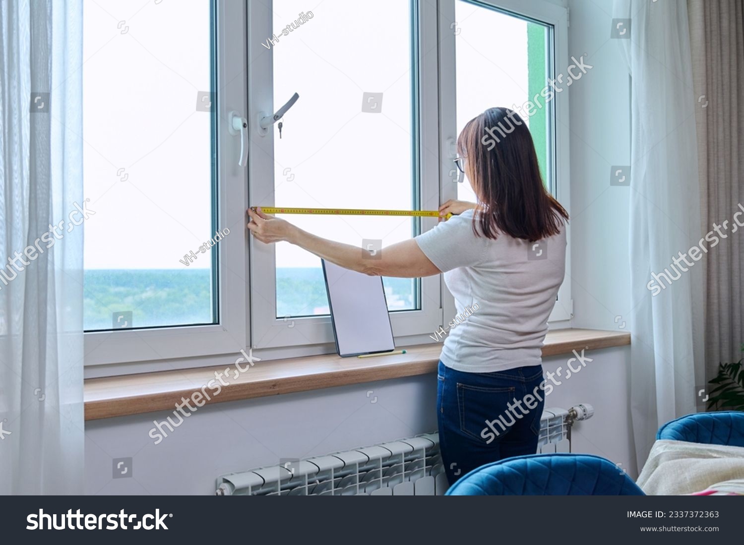 Woman measuring window with tape measure, tailoring service #2337372363