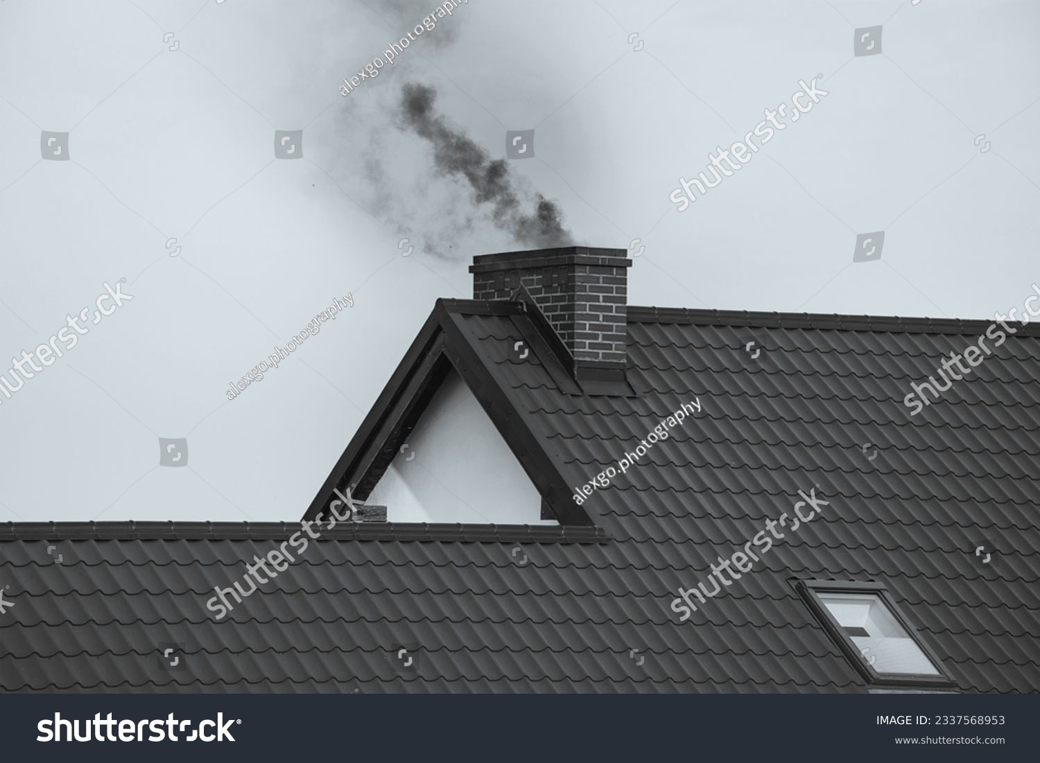 Dark smoke comes out of the chimney of a modern house in winter. Heating with solid fuel. The concept of environmental pollution #2337568953