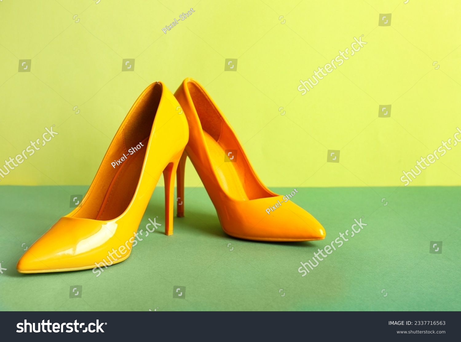 Pair of stylish high heeled shoes on green background #2337716563