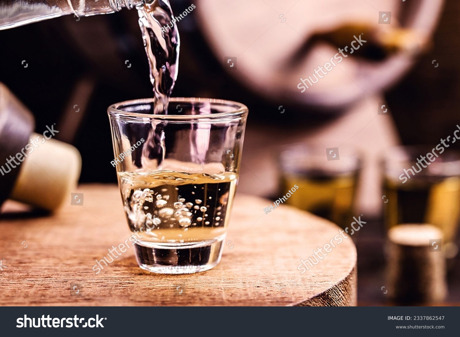 Glass of golden rum, with bottle. Bottle pouring alcohol into a small glass. Brazilian export type drink. Brazilian product for export, distilled drink known as brandy or pinga. Day of cachaça. #2337862547