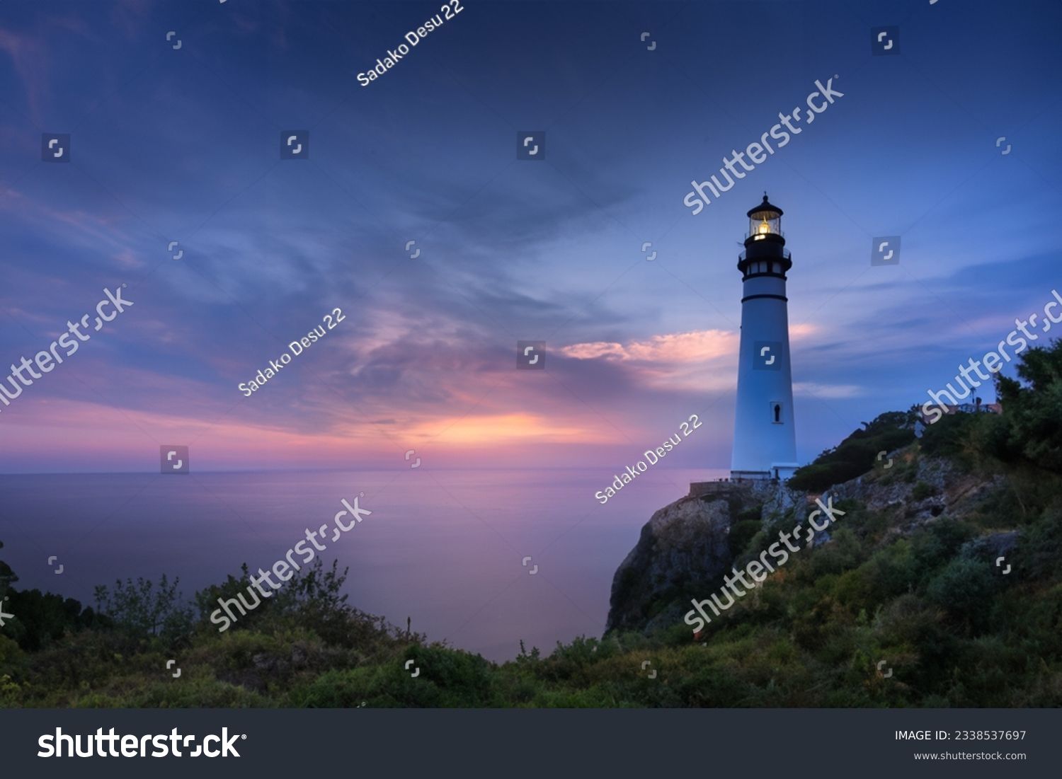 Coastal Security: Illuminated Lighthouse Guides Travelers to Protected Beach at Sunset #2338537697