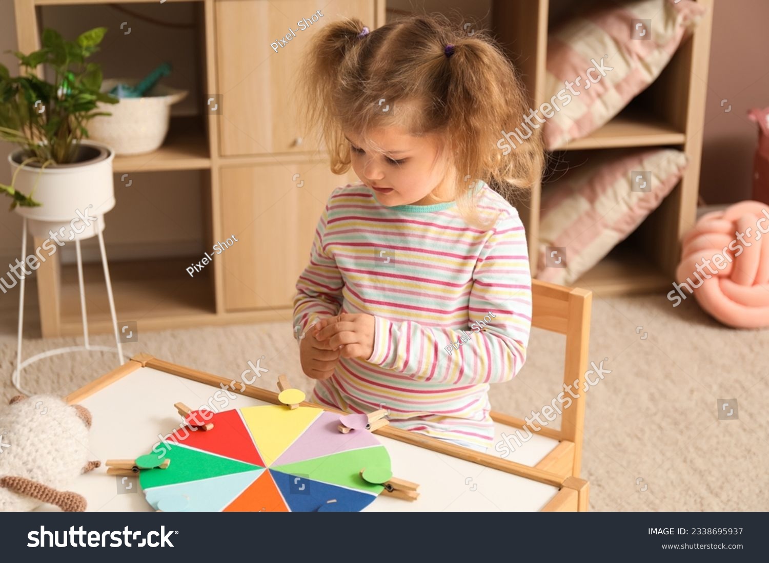 Cute little girl playing matching game with clothespins at home #2338695937