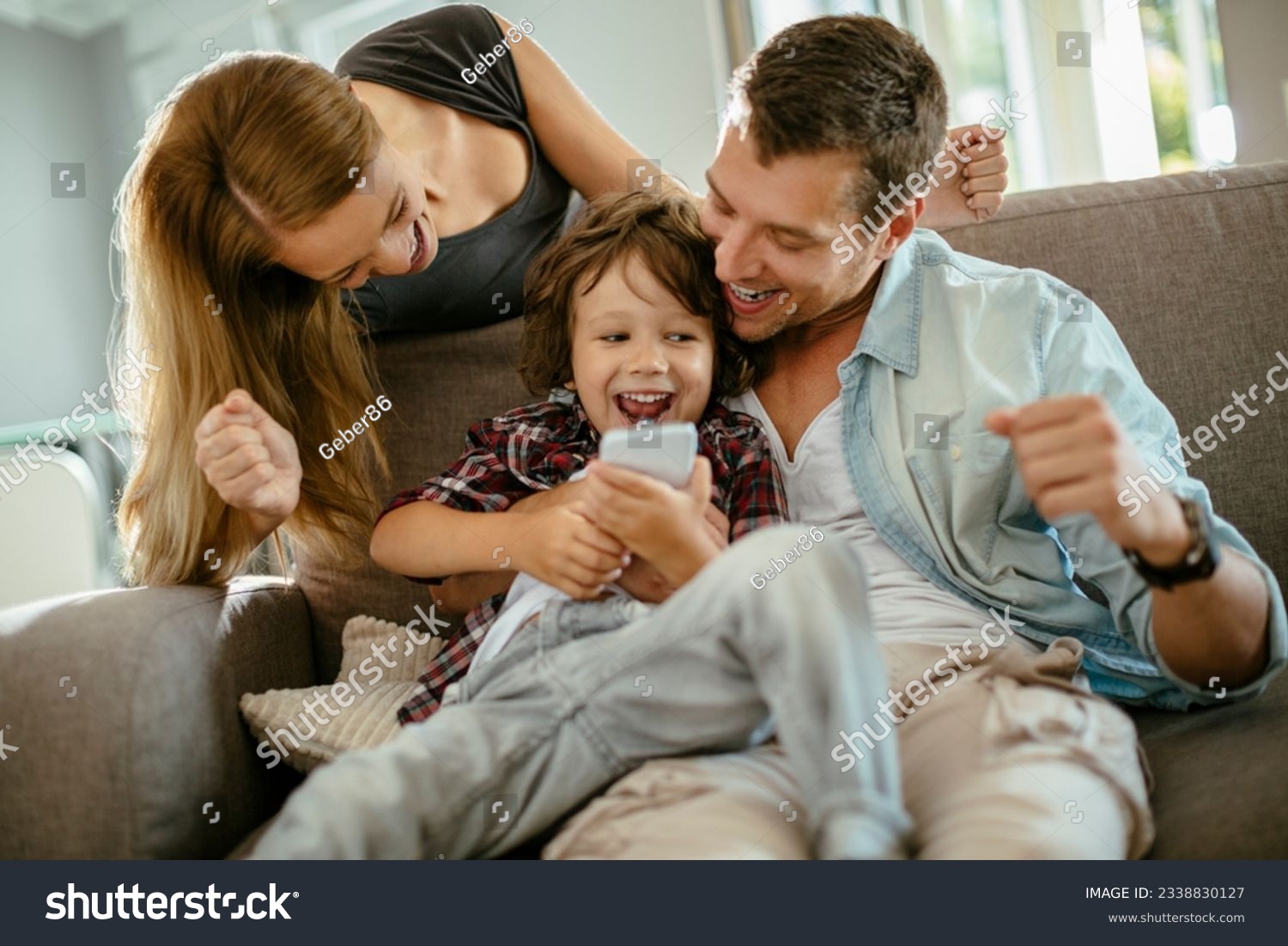 Young family using a smart phone while sitting on the couch in the living room #2338830127
