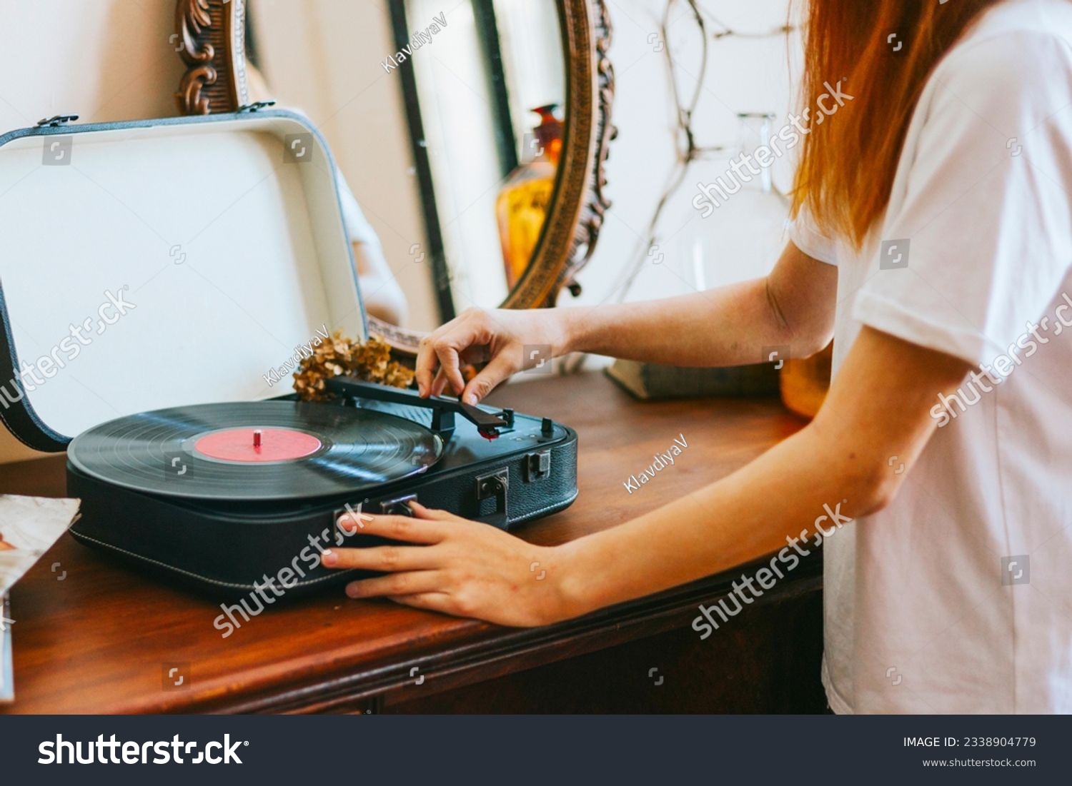 A modern teenage girl with dyed hair turns on a retro record player, meeting modern with retro #2338904779